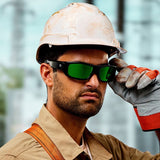 A construction worker wearing a white hard hat, gloves, a brown work shirt, and Lucyd Armor | Green Mirror Polarized safety glasses by Lucyd looks forward while adjusting his glasses. The background is blurred.